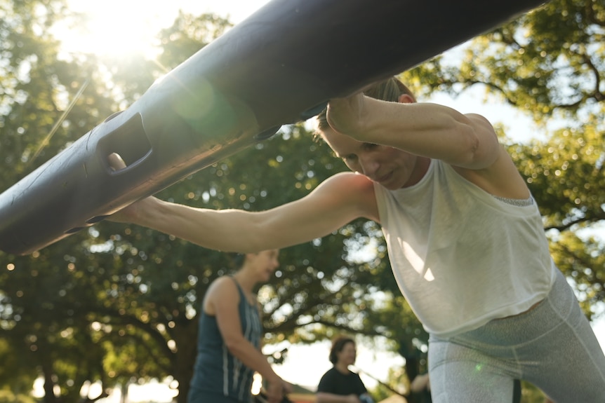 A woman takes part in an exercise class outdoors.