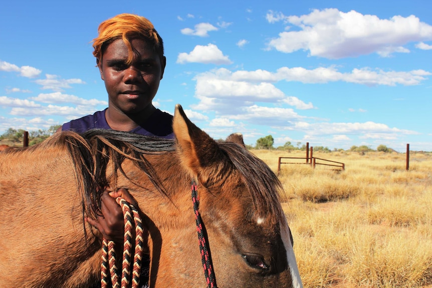 A profile shot of 14-year-old Marley Kantawara next to his horse