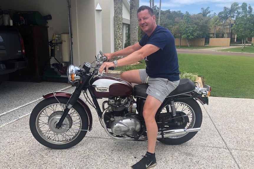 Man sitting on top of a restored 1971 Triumph. 