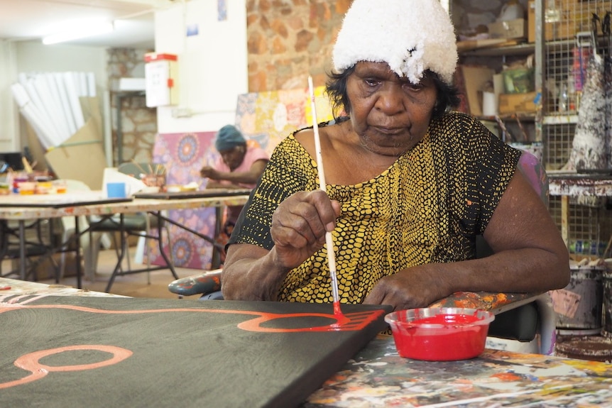 A woman paints a painting on a flat table