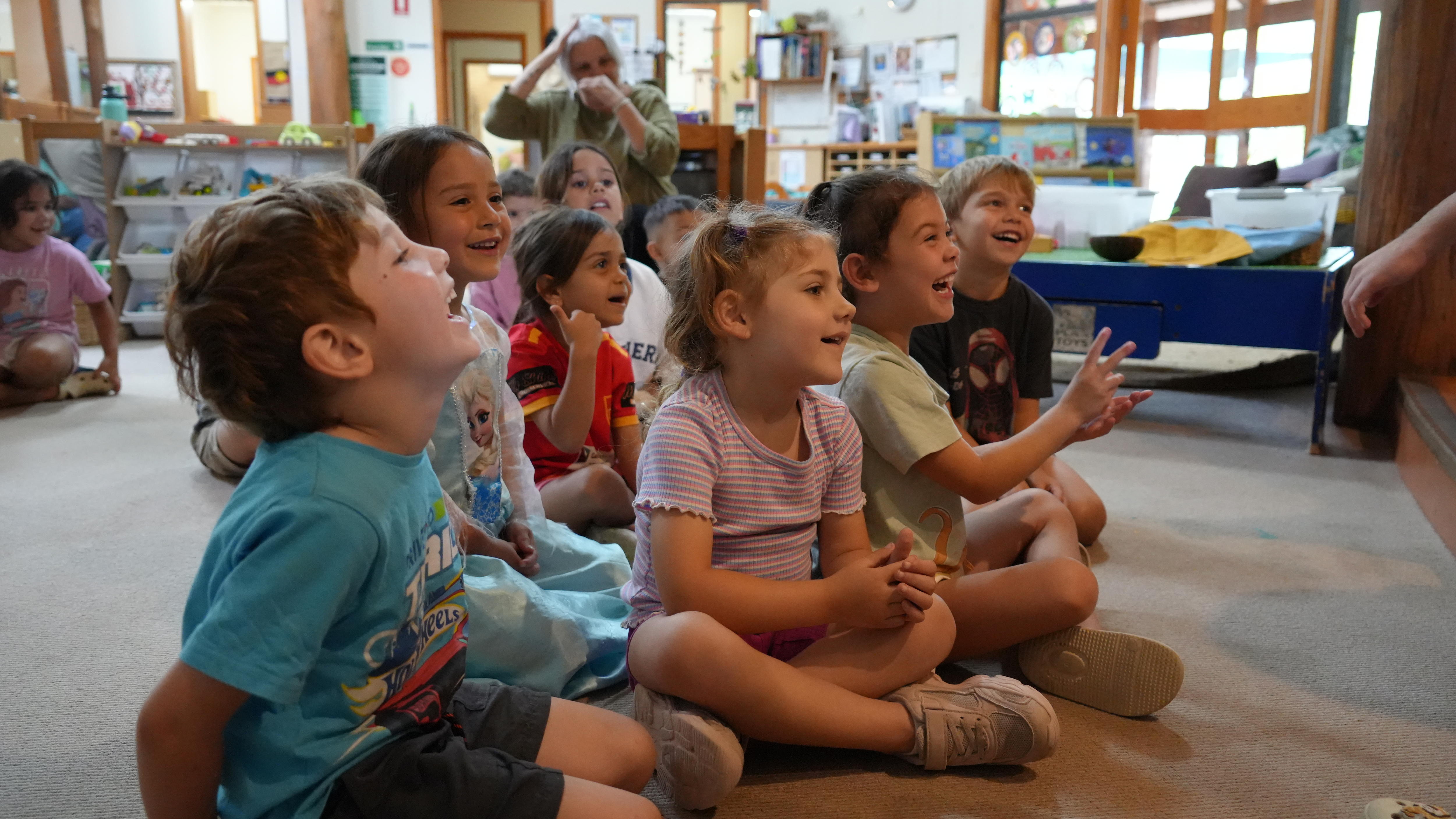 A group of preschool children sitting on the floor together laughing