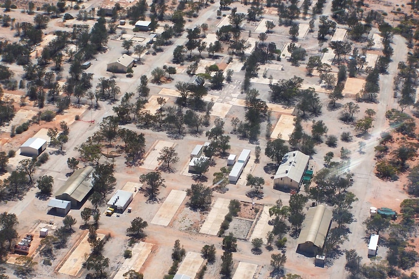 An overhead shot of square army barracks.  There is red dust around them.