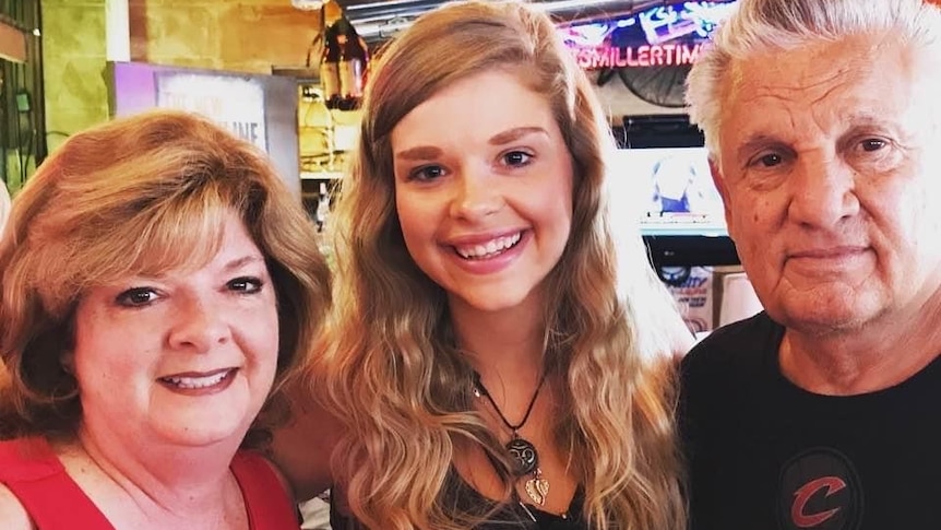 A young woman smiles with her parents.