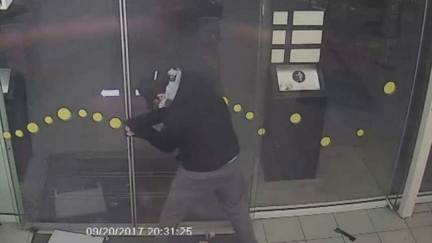 A thief tries to force his way out of the petrol station he robbed.
