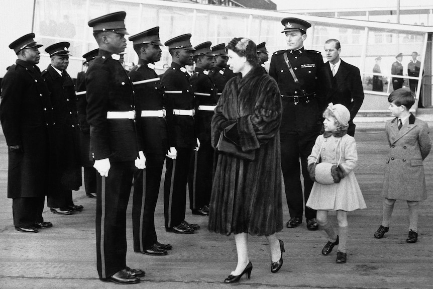 Fur-coated Queen Elizabeth II and her husband and children greets guards.