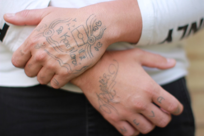 Two hands with tattoos clasped together.
