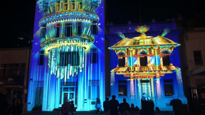 a gothic building has lights shown on it.