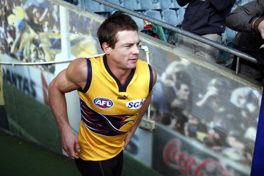 A mid-shot of Ben Cousins in a yellow West Coast Eagles training jumper running from the players' race at Subiaco Oval.