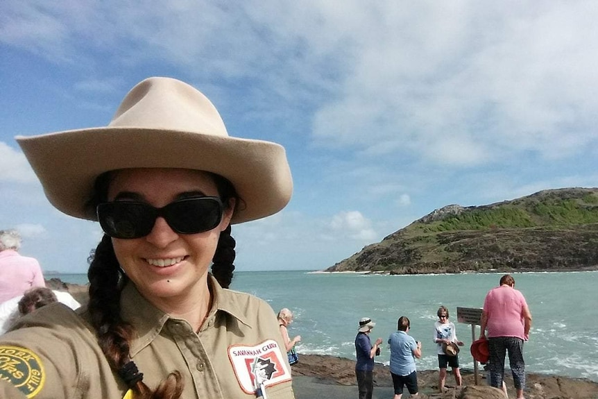 Woman with big hat stands beside the sea