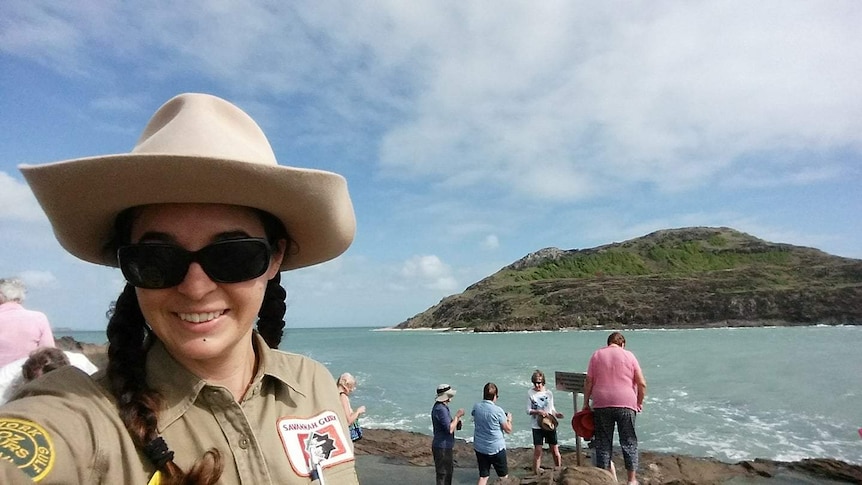 Woman with big hat stands beside the sea