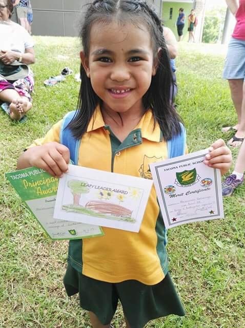A five-year-old girl holding a school award