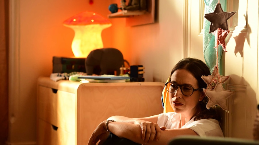 Audrey (Alison Bell) sits against a door in her daughter's room