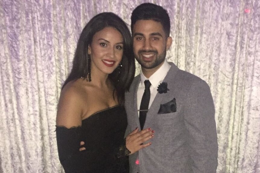 Anmol Sekhon stands with his wife in formal attire at an event