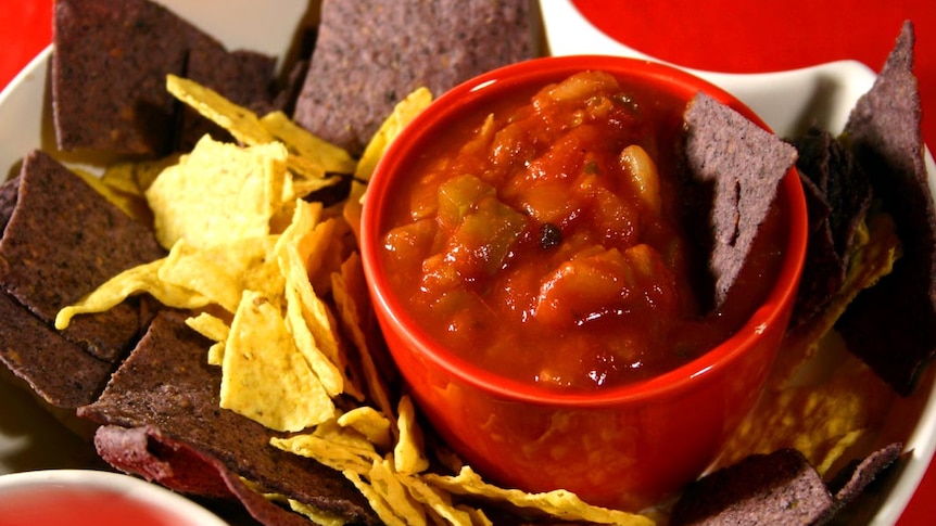 A bowl of salsa with corn chips.