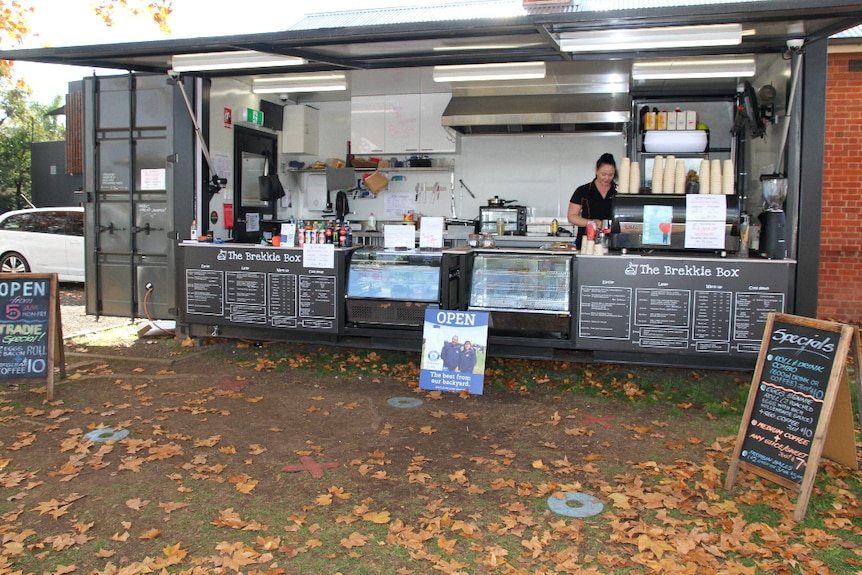 A wide view of The Brekkie Box cafe in Wodonga. A worker makes coffee.