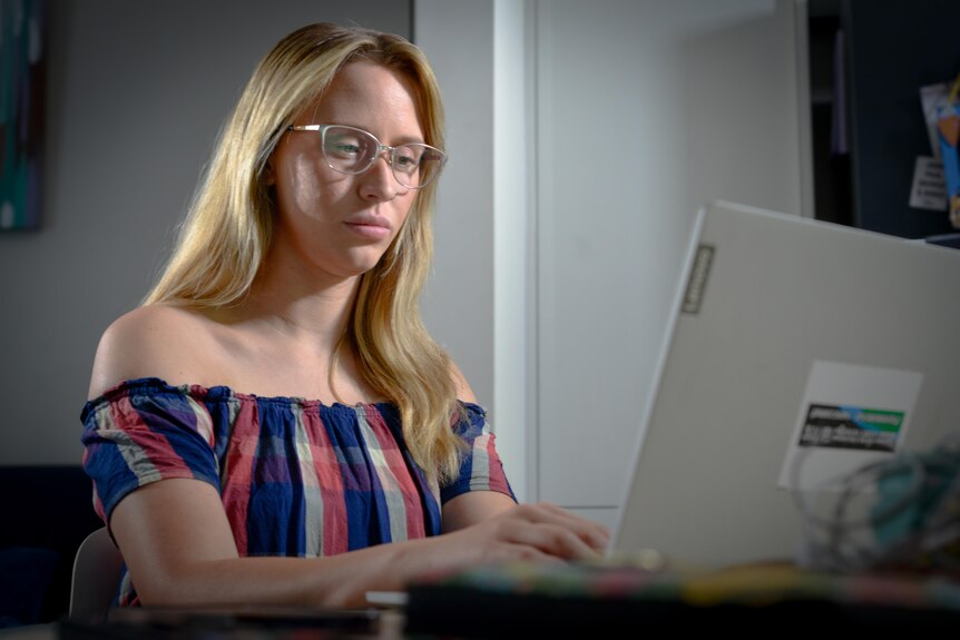 Una mujer joven sentada frente a una computadora.