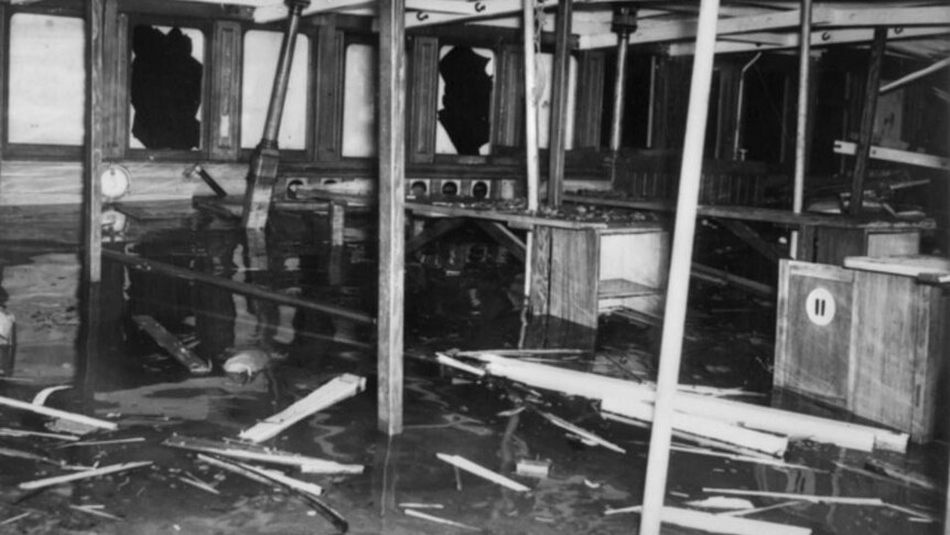 Interior of the top deck of the HMAS Kuttabul showing splintered wood and damaged windows.