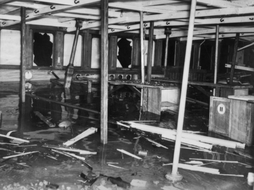 Interior of the top deck of the HMAS Kuttabul showing splintered wood and damaged windows.