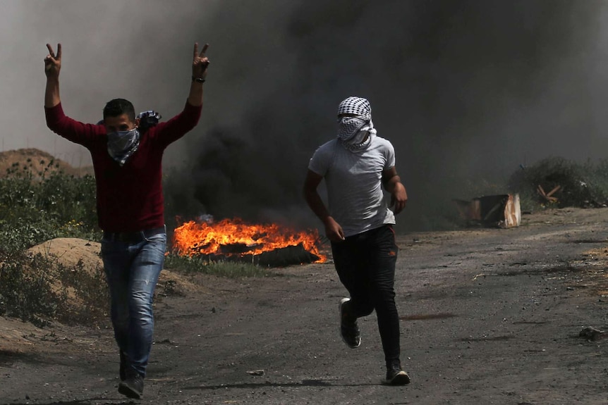 Two men are seen running near a pile of burning tyres as the violence unfolds.