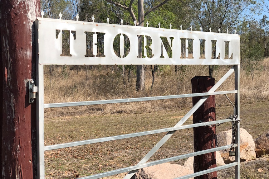A metal signed gate reading Thornhill with scrubland behind it