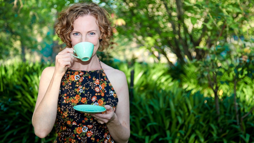 A white woman sipping tea from a lime green cup