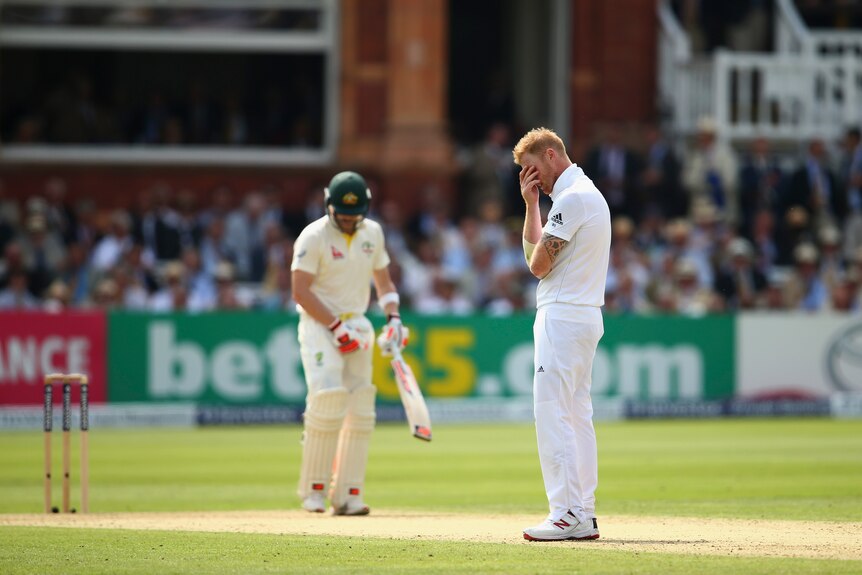 Steve Smith looks at the pitch as Ben Stokes holds his face