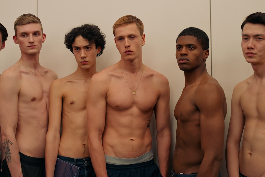 A group of shirtless male models staring seriously