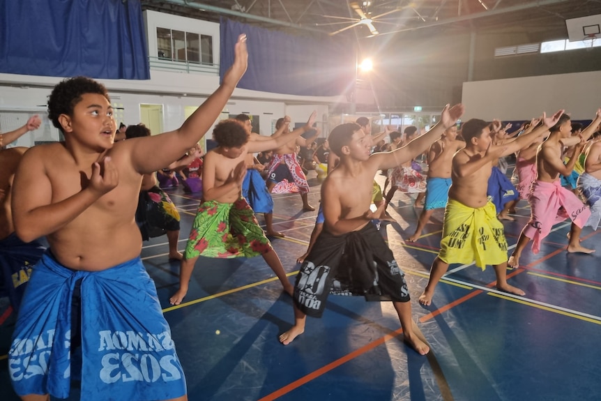 Rows of teenage Samoan boys wear ie lava lava as they perform fa'ataupati.