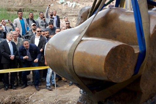 Onlookers watch as the torso of an ancient Egyptian pharaoh statue is excavated in a Cairo suburb.