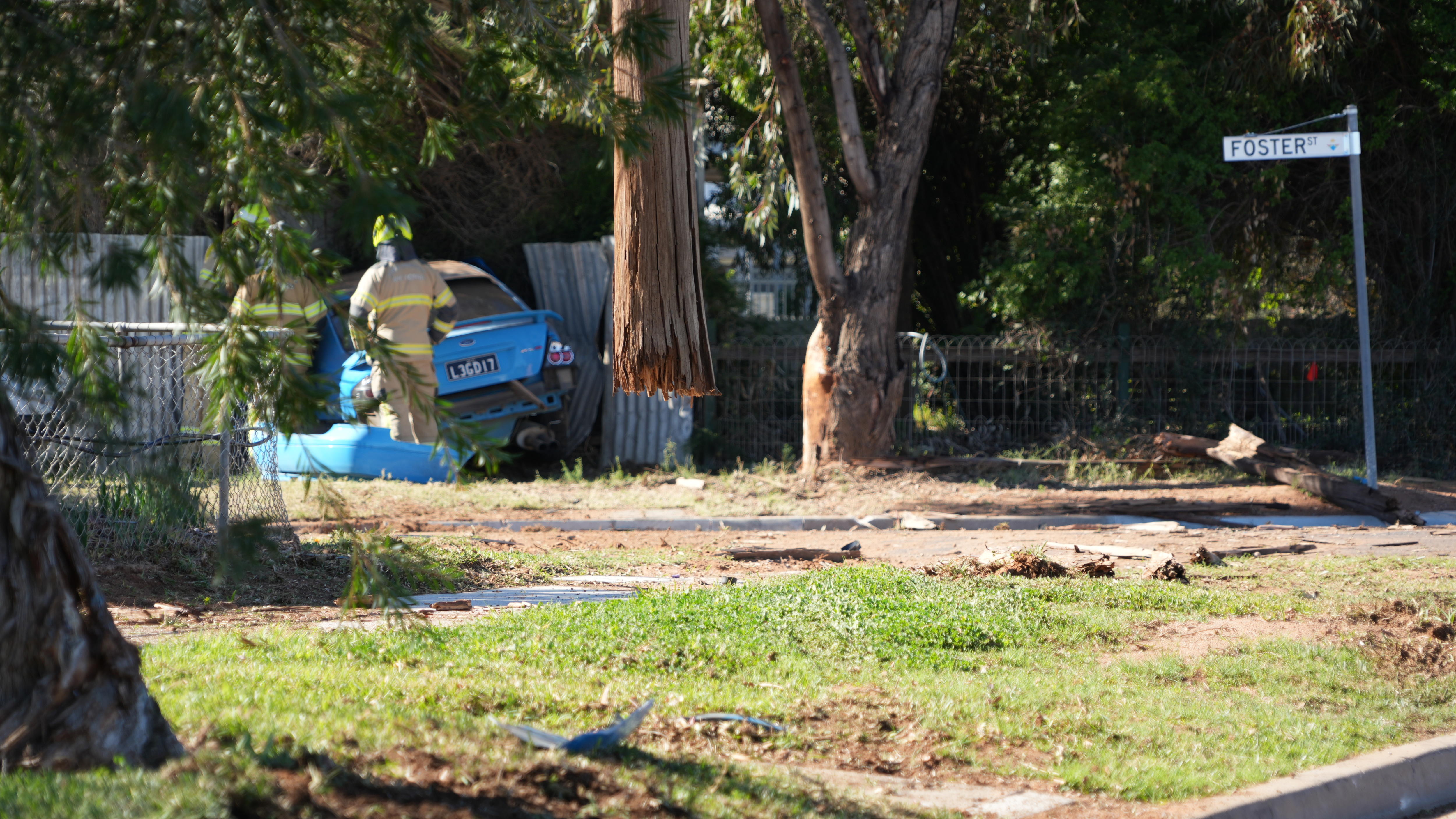Two firefighters inspect a blue car which crashed through a power pole and into the side of a home