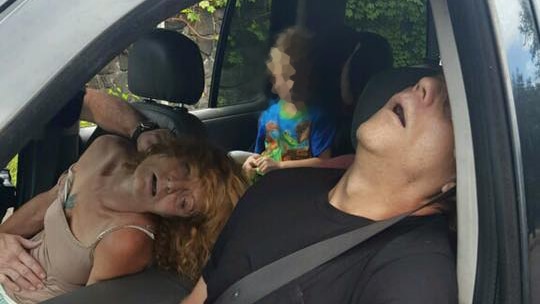 Unconscious couple sit in car with child