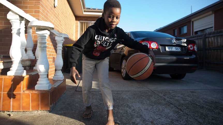 Eight-year-old Maher wearing a Chicago Bulls jumper dribbles his basketball in the driveway.
