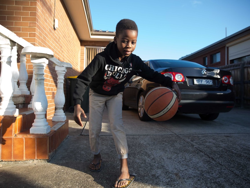 Eight-year-old Maher wearing a Chicago Bulls jumper dribbles his basketball in the driveway.