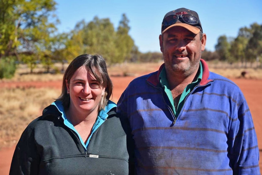 a woman and a man looking at the camera with trees in the background.