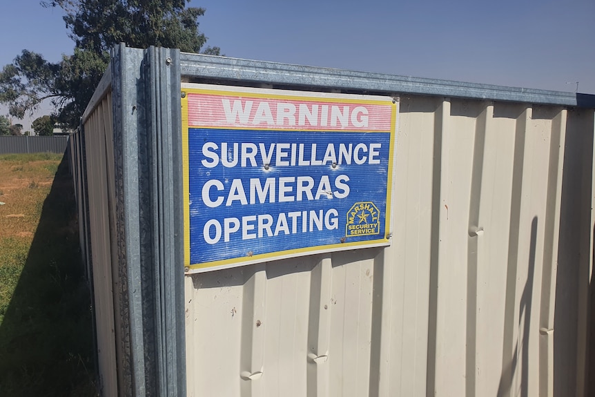 A surveillance camera sign on a fence.