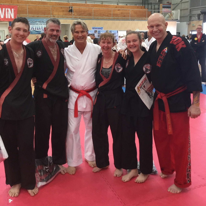 Samuel, Damian, Megan and Caitlyn Pitts posing for a photo with high ranking Zen Do Kai leaders in a gymnasium.