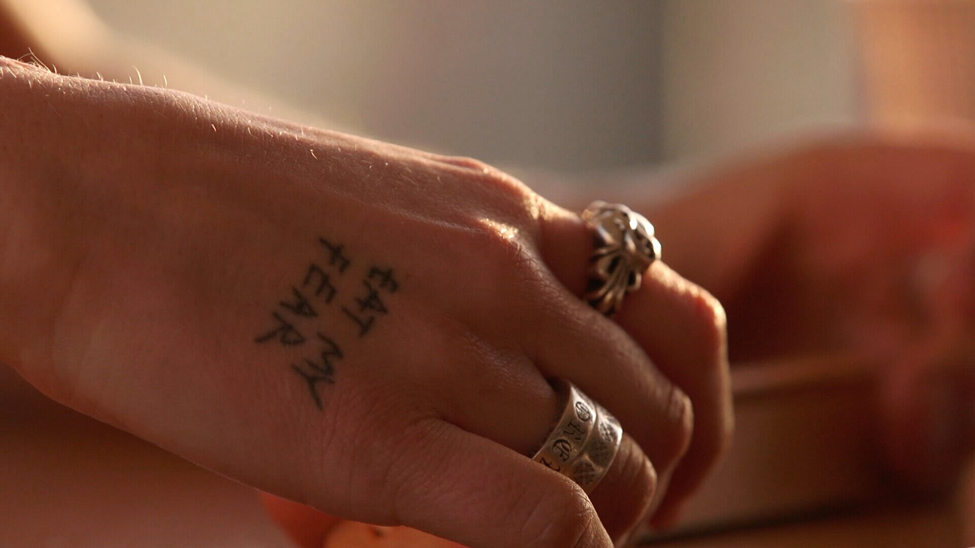 Tattoo on the hand Grace Tame reads "eat my fear" in black text