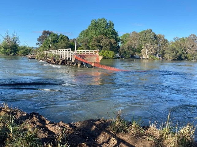 Floodwater surges under a collapsed bridge