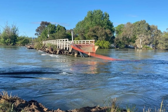 Floodwater surges under a collapsed bridge