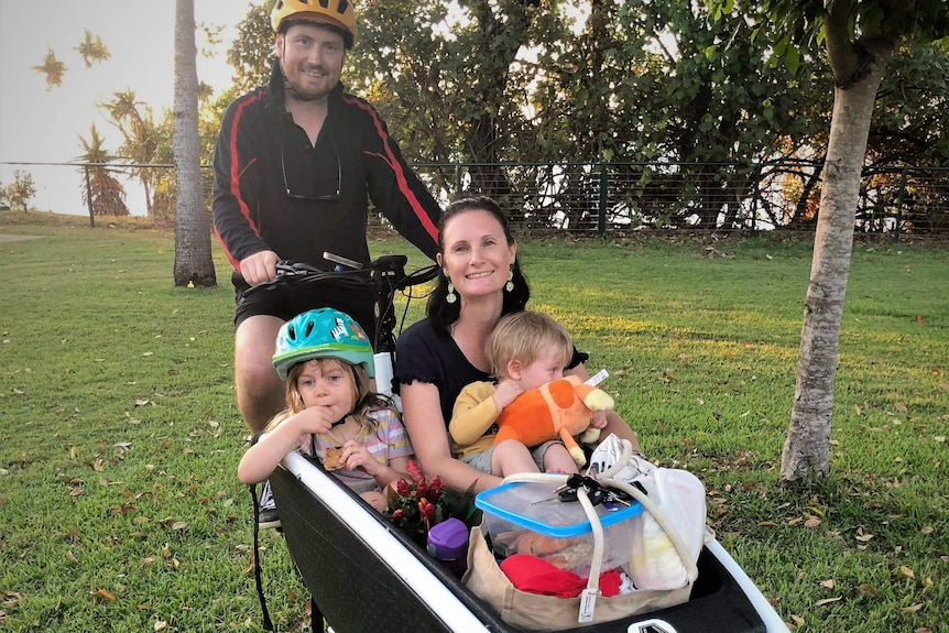 Dad on the saddle with mum, two kids, and loads of stuff in the box of a cargo bike.