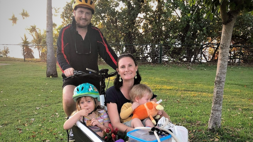 Dad on the saddle with mum, two kids, and loads of stuff in the box of a cargo bike.