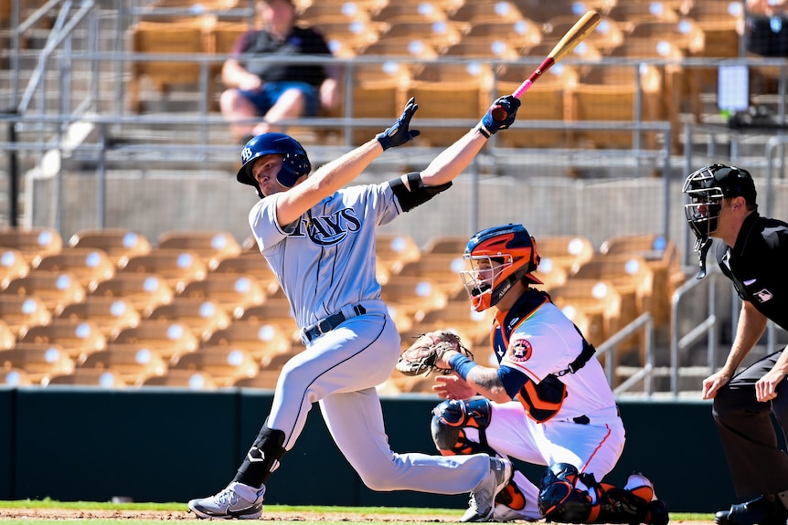 A male baseball player follows through after hitting the ball in a US minor-league game.