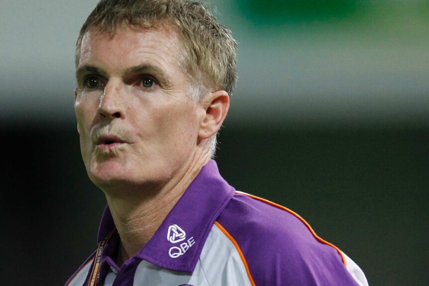 A mid shot of Perth Glory's then-interim coach Alistair Edwards with his lips pursed and wearing a white and purple Glory shirt.