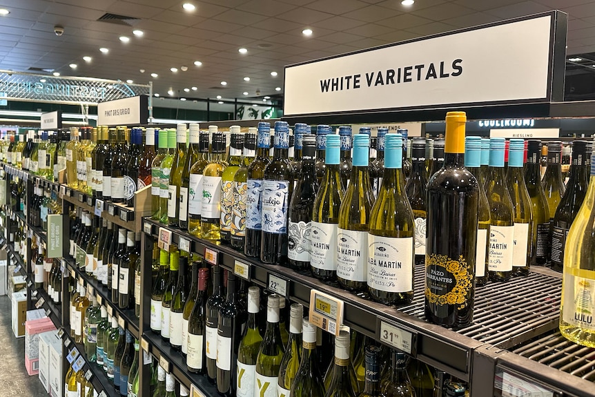 Un estante de vino blanco varietal a la venta en una tienda. 