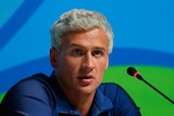 Ryan Lochte speaks into a microphone during an Olympics press conference.