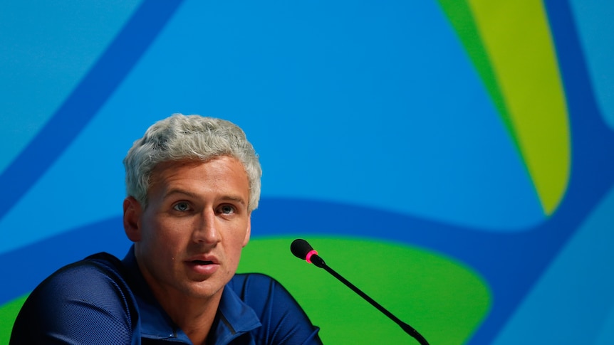 Ryan Lochte speaks into a microphone during an Olympics press conference.