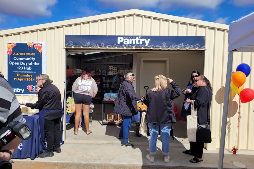 A shed that has been turned into a grocery store with customers gathered outside 