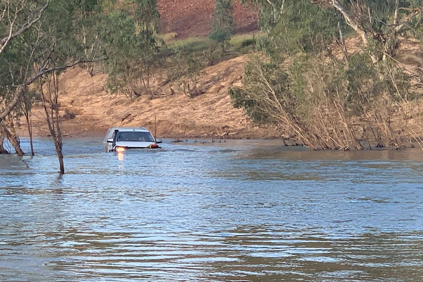 Un quatre roues motrices tente de traverser une route inondée, presque submergée