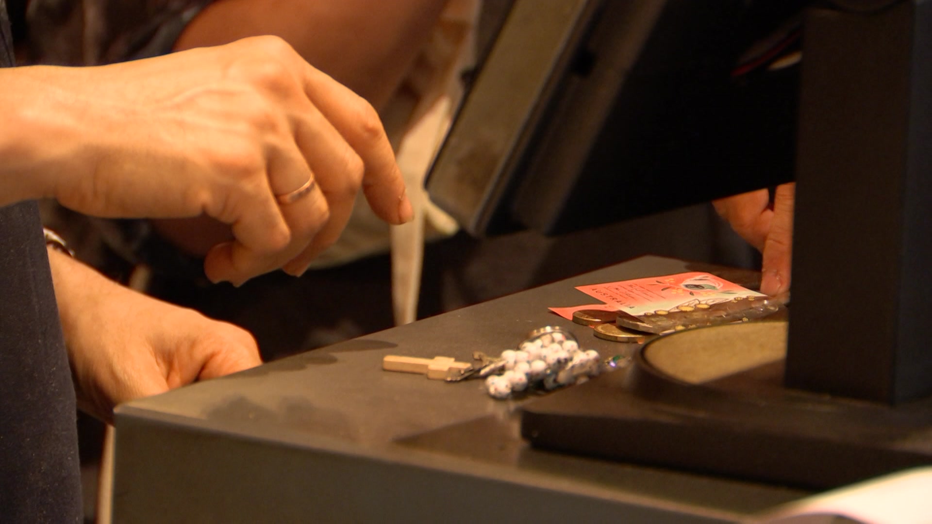 A persons hands reaching to pick up cash off a counter.
