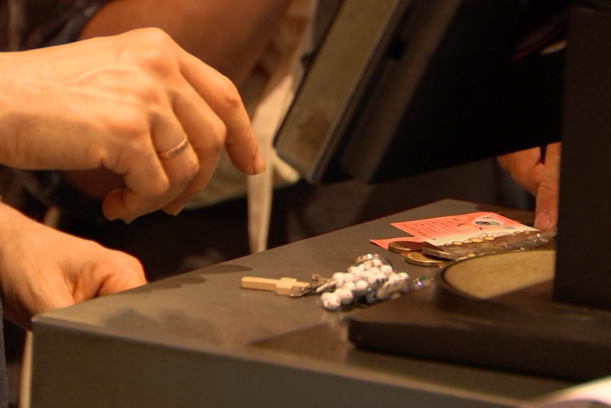 A persons hands reaching to pick up cash off a counter.
